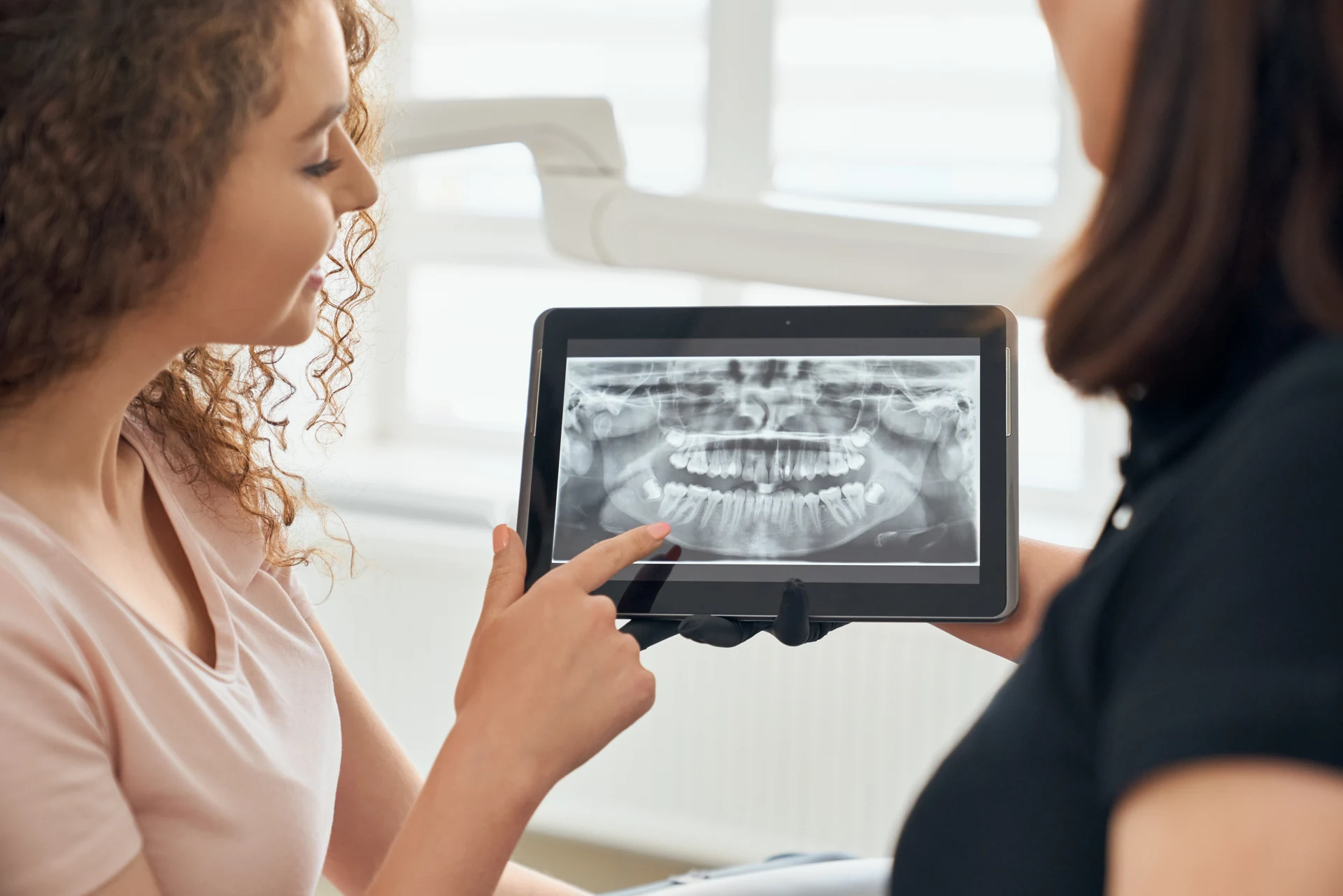 A patient and dental professional reviewing a panoramic dental X-ray for treatment planning