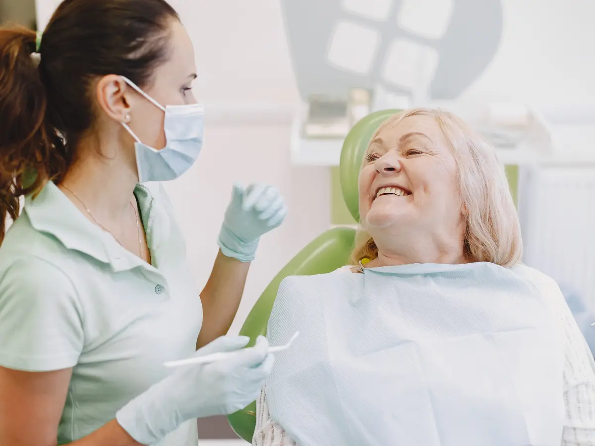 A senior patient smiling during a conversation with her dental clinician