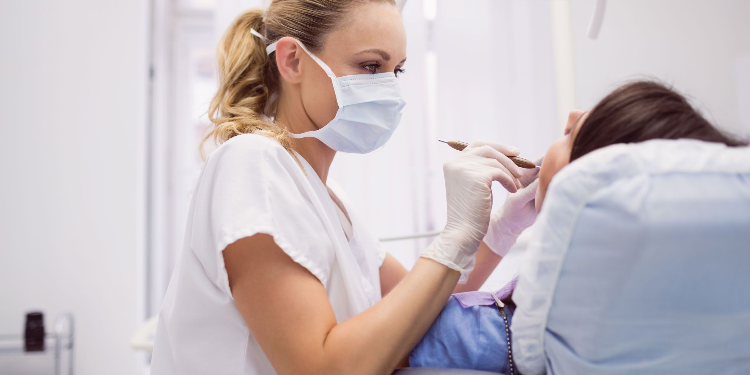 A dentist examining an adult patient's tooth before restorative care