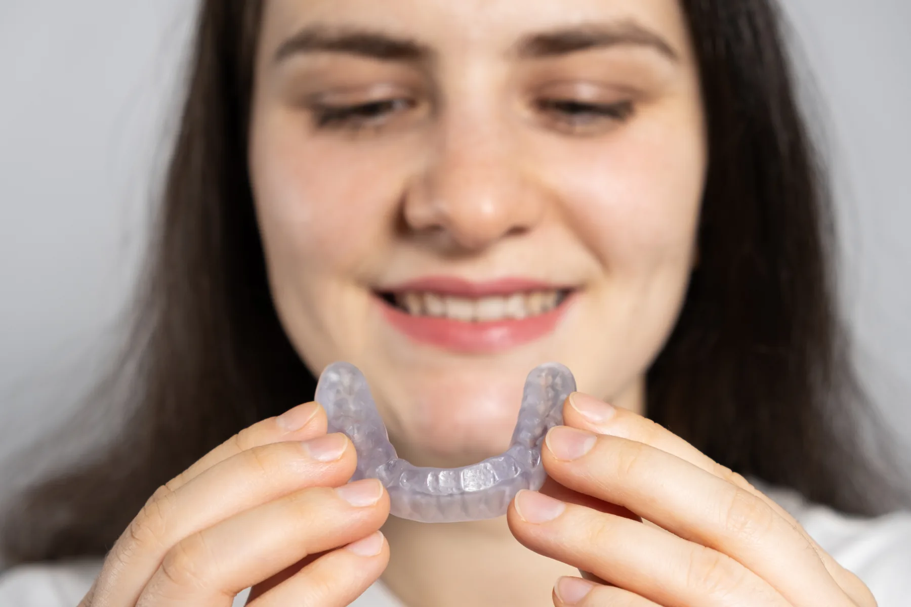 A woman holding a custom nightguard for bruxism protection