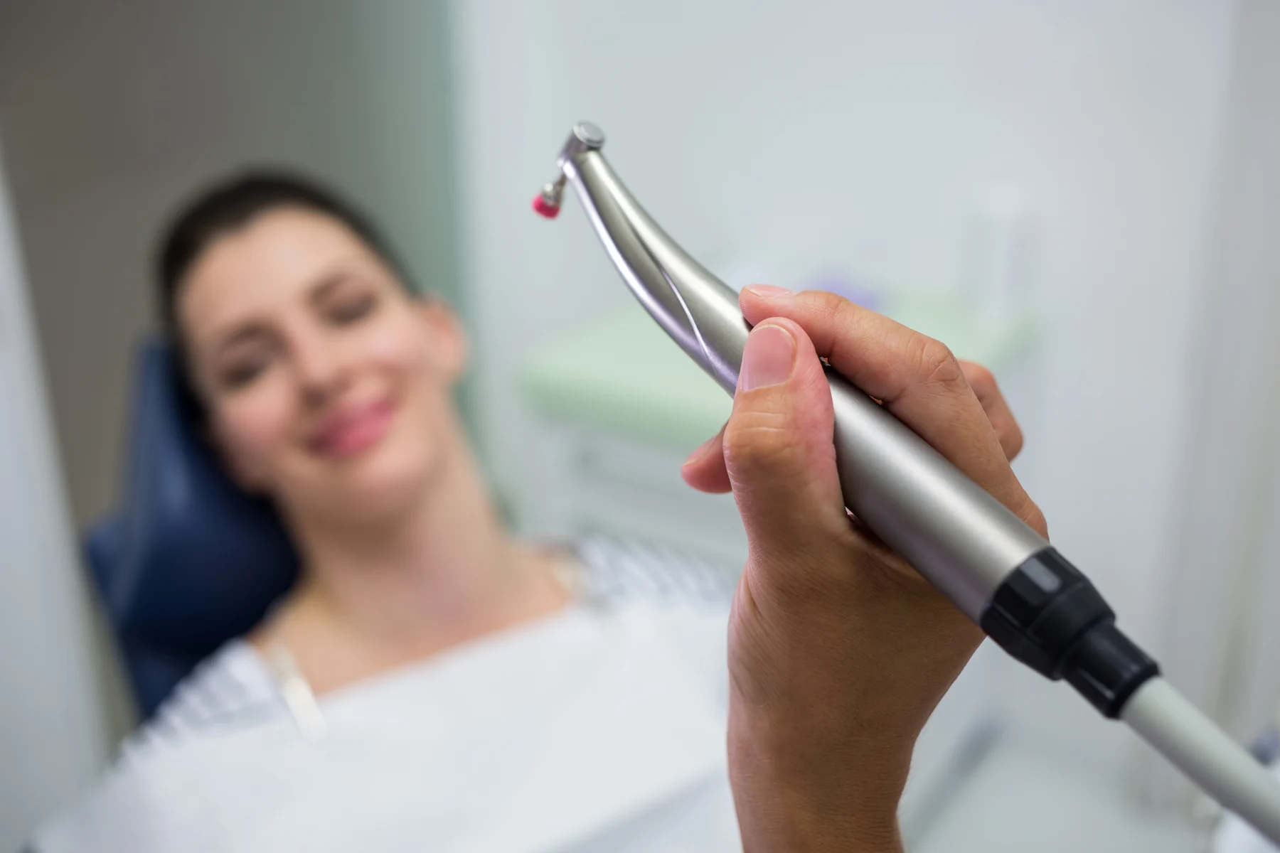 A dental professional preparing a gentle polishing handpiece for an adult patient's cleaning