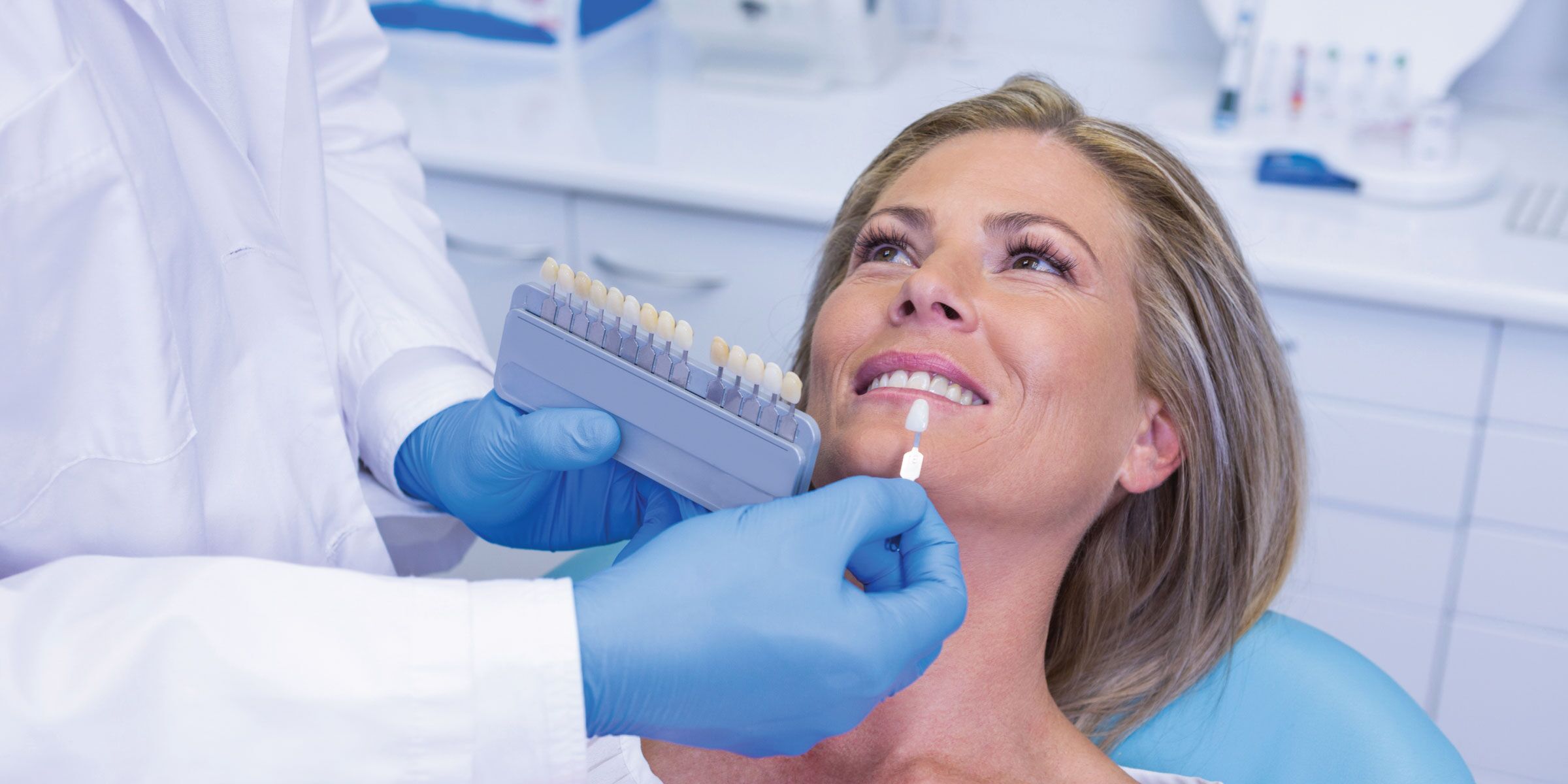 A dentist selecting a natural shade for an adult patient's dental crown